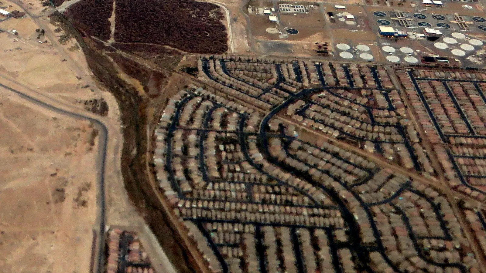 Aerial view of housing developments and desert land at the edge of Henderson, Nevada