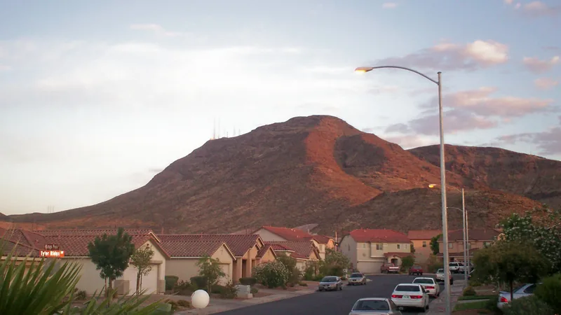 Houses along a Henderson street below a red-lit hill at dusk
