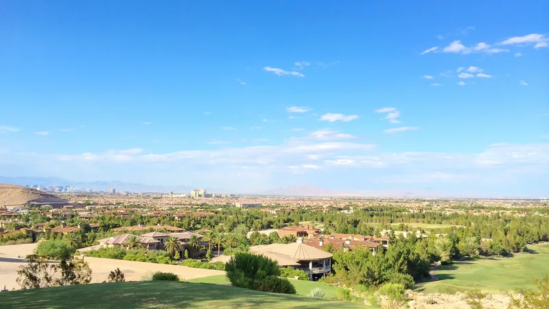 View from a grassy hillside in Southern Highlands over tile-roofed homes and the valley toward distant buildings