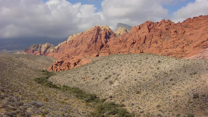 Red sandstone Calico Hills and desert scrub under blue sky and clouds at Red Rock Canyon National Conservation Area