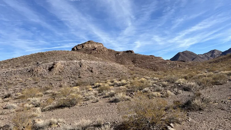 Desert hills with scrub brush and wispy clouds on a trail in the McCullough Hills, Sloan Canyon National Conservation Area