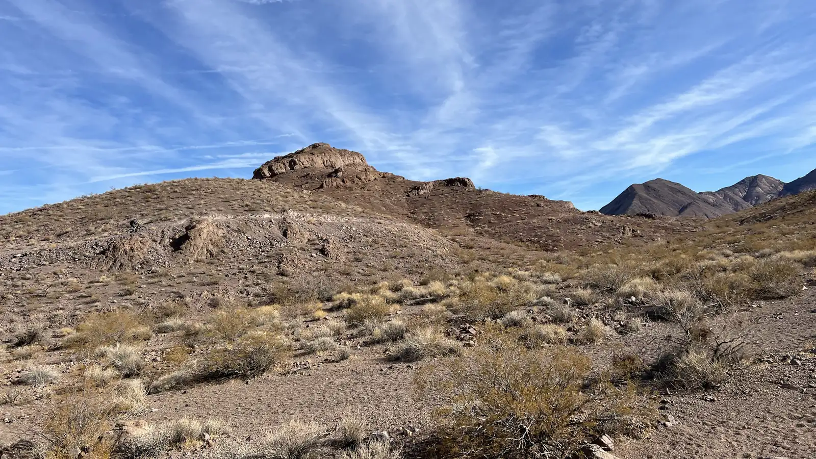 Desert hills with scrub brush and wispy clouds on a trail in the McCullough Hills, Sloan Canyon National Conservation Area